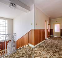 A hallway in a family house with wooden paneling and a patterned carpet.