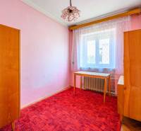 A room in a family house with pink walls, furniture, and a red carpet.