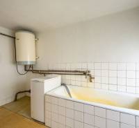 Bathroom in a family house with a bathtub, boiler, and washing machine.