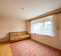 A room in a family house with a carpet, a couch, and a large window.