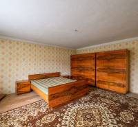 Bedroom in a family house with wooden furniture and retro patterns on the walls.