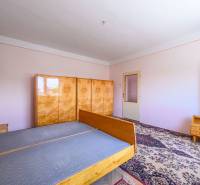 A bedroom in a family house with wooden furniture and a carpet on the floor.