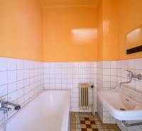 A bathroom in a family house with a bathtub, a sink, and tiles on the wall.