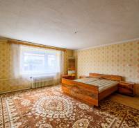 Bedroom with a bed, patterned wallpaper, and carpets in a family house.