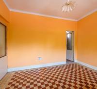 A room in a family house with orange walls and a tiled pattern on the floor.