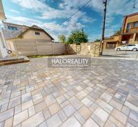 A paved courtyard at a family house in Rimavská Sobota with a fence and parking spaces.