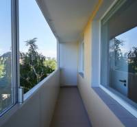 A glazed balcony in a 2-room apartment with a view of greenery.