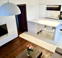 A bright kitchen in a 2-room apartment with a wooden floor, table, and flowers.