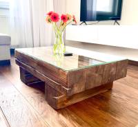 Glass table with a wooden frame and flowers in a vase in a 2-room apartment.