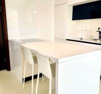 A kitchen in a 2-room apartment with white furniture and a bar counter with stools.