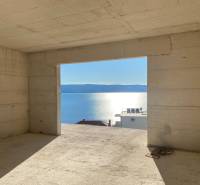 An unfinished interior of a villa with a view of the sea and a sunset in the background.