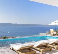 View from the villa in Duće of the sea, terrace with a pool, sunbeds, and umbrellas.