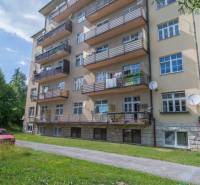 A five-story apartment building in the High Tatras with balconies and a green lawn.