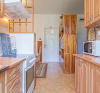 A kitchen in a 3-room apartment with a stove, microwave, and wooden cabinets.