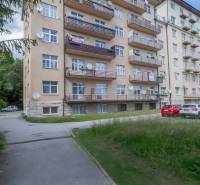 An apartment building in the High Tatras with balconies and a parking lot in front of the building.