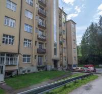 A five-story apartment building in the High Tatras with an access road and parking.