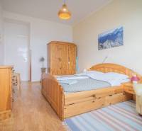 A bedroom with wooden furniture, a painting of mountains, and wicker decorations in a 3-room apartment.