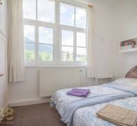Bedroom in a 3-room apartment with a large window and a view of the mountains.