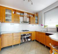 The kitchen of a family house with light wooden furniture and appliances, spacious work surface.