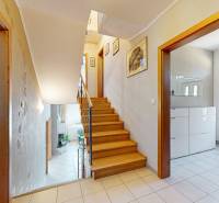 Interior of a family house with wooden stairs and a bright hallway with tiles.
