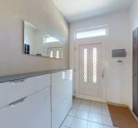 The entrance hall of a family house with white doors, a mirror, and shelves.