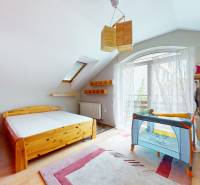 A bright room with a wooden bed and a crib in a family house.
