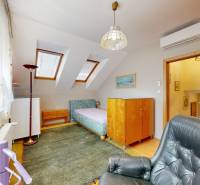 Attic room with a bed, chair, and wooden furniture in a family house.