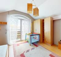 Children's room with a crib, wooden wardrobes, and a large window in a family house.