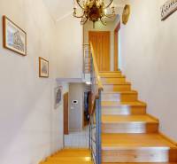 Wooden staircase with metal railing, paintings on the walls, chandelier in a family house.