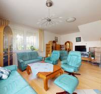 Living room in a family house with light sofas, a wooden table, and a television.