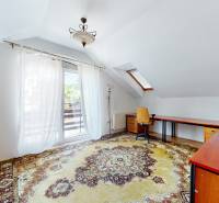 A room in a family house with a large carpet, a desk, and balcony doors.