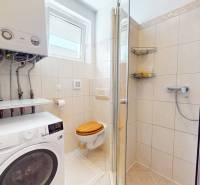 Bathroom in a family house with a washing machine, shower, and gas boiler.