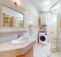 A bathroom with a washing machine, shower, and boiler in a family house.