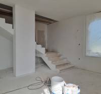 The staircase in the Villa during renovation, next to a large window with a covered view.