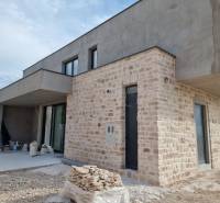 A villa in Vodice with a structured stone cladding and a terrace, nearing completion.
