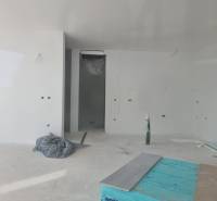 An unfinished room in a villa with white walls and an incomplete floor.