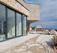 Construction of a villa in Vodice with a glass wall and a construction site on the coast.