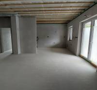 A spacious interior of a family house with a concrete floor and a wooden ceiling.