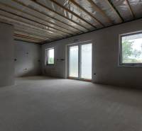 The interior of a family house with unfinished walls and a view of the windows and terrace.
