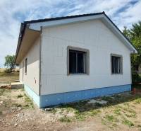 A family house in Kozárovce with an unplastered facade and an adjacent plot of land.