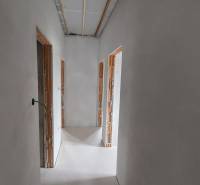 A hallway in a family house with unfinished door openings and white walls.