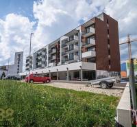 A building in the town of Svit with commercial spaces and a parking lot in the foreground.