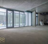 Unfinished commercial spaces with glass walls and a concrete ceiling.