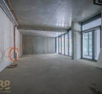 Interior of commercial premises with a glass wall, concrete ceiling, and electrical installation.