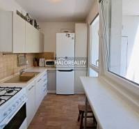 A kitchen in a 3-room apartment with white cabinets, a gas stove, and a window.