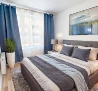 A bright bedroom with a comfortable bed, television, and striking blue curtains in a 2-room apartment.