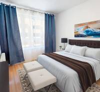 A bedroom with a bed, dark blue curtains, and a painting in a 2-room apartment.