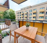 Balcony of a 2-room apartment with a wooden table and chairs, view of the surrounding building.