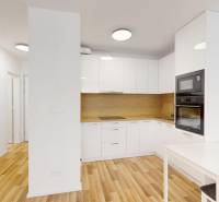 A kitchen in a 2-room apartment with wooden flooring and built-in appliances.