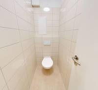 Bathroom door in a 2-room apartment with a white toilet and light tiles.